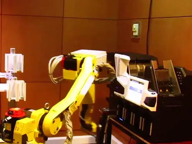 Robot industrial junto a una clasificadora de billetes de varios bolsillos, en una celda que retira las lenguas ya clasificadas