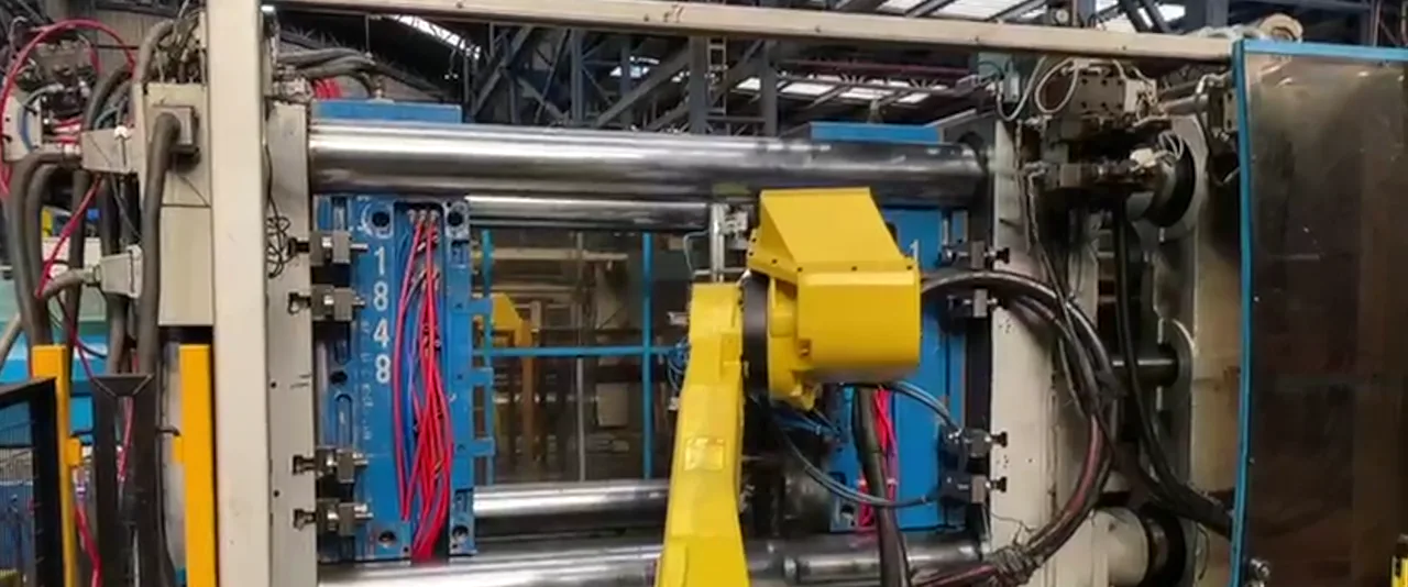Robot atendiendo una máquina de inyección de plástico