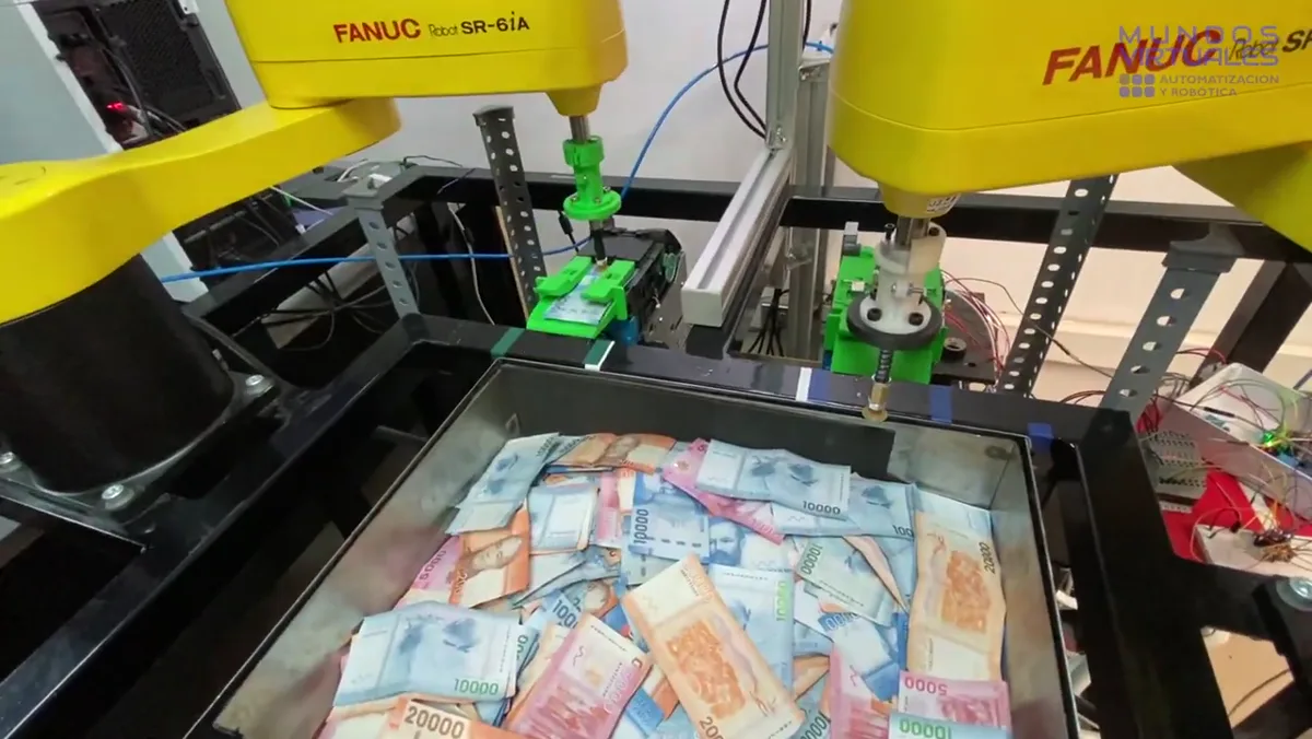 Celda con dos robots FANUC coordinados manipulando billetes